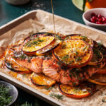 A baking sheet with the citrus broiled salmon on top, with a drizzle of olive oil actively being poured on top of it
