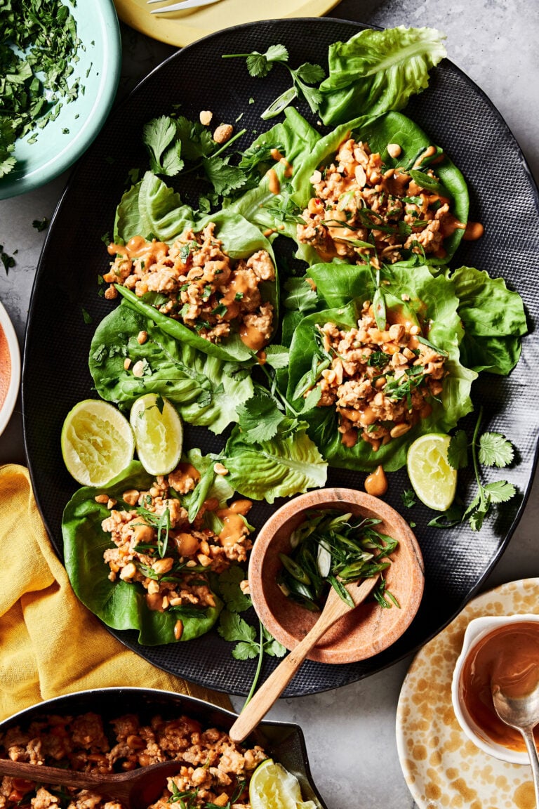 A plate of the peanut chicken lettuce wraps, sitting on a countertop with a small bowl of sauce sitting next to them