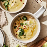 A bowl of the zesty cauliflower leek soup, sitting on a countertop with a second bowl in the background