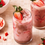 A tall glass of the copycat starbucks chocolate covered pink drink, sitting on a countertop with a second drink in the background