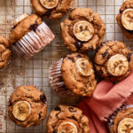 A batch of the finished banana chocolate chip protein muffins, laid out on a wire cooling rack