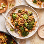A plate of the saucy cashew chicken and broccoli, sitting on a countertop with a fork sitting on the plate