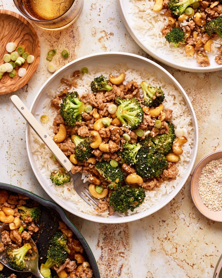 A plate of the saucy cashew chicken and broccoli, sitting on a countertop with a fork sitting on the plate