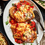 A plate of the quick and easy chicken parmesan, sitting on a countertop with a spatula sitting in the bowl