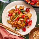 A plate of the healthier kung pao chicken, sitting on a countertop with chopsticks resting on the edge of the plate