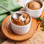 Two ramekins of the single serving carrot cake baked oats, sitting on a countertop with a spoon tucked inside of one of them
