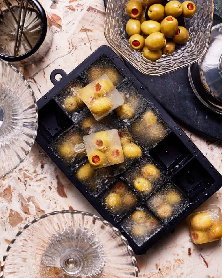 An ice cube tray, filled with the dirty martini olive cubes
