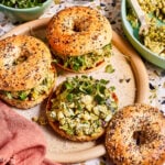 A plate of the herby avocado egg salad, sitting on a bagel on a countertop