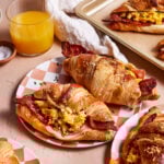 A plate of the best ever croissant breakfast sandwiches, sitting on a plate on a countertop