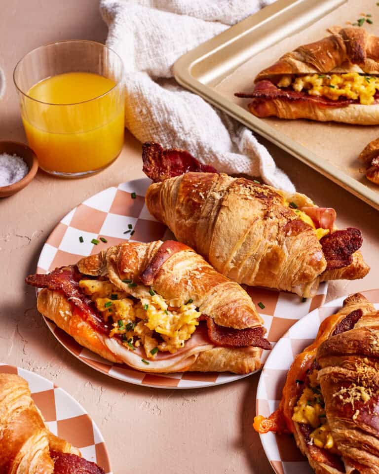 A plate of the best ever croissant breakfast sandwiches, sitting on a plate on a countertop