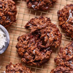 A close-up image of one of the german chocolate magic cookies, broken in half and sitting on top of a wire cooling rack
