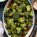 Steamed broccoli with sesame seeds in a white serving dish.
