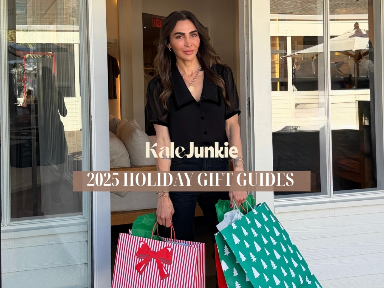 A woman stands in an open doorway holding colorful holiday gift bags. Text reads "Kale Junkie 2025 Holiday Gift Guides." The scene appears festive and cheerful.