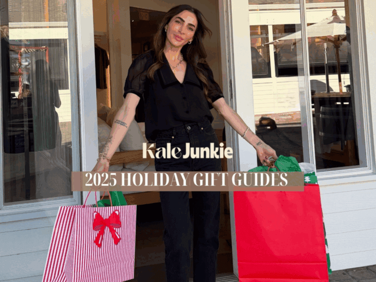 A smiling woman in black clothes stands outside a shop holding large red gift bags. The text reads "Kale Junkie 2025 Holiday Gift Guides.