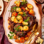 A platter of pot roast with roasted potatoes and carrots, garnished with fresh parsley.