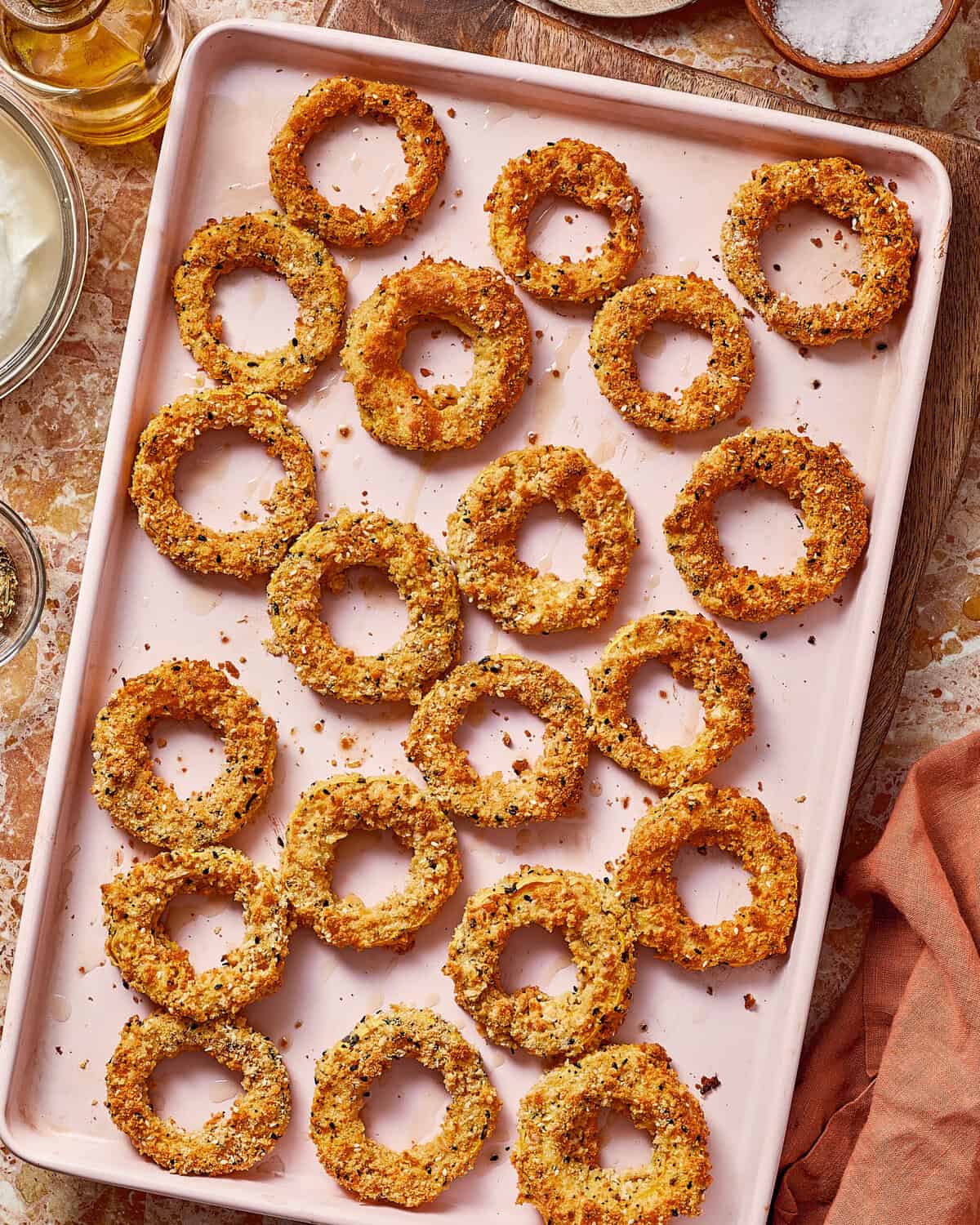 A rectangular tray filled with golden-brown breaded onion rings.