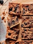The grain-free blueberry coffee cake, cut into squares, and laying out on a sheet of parchment paper