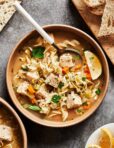 A bowl of the cozy turkey noodle soup, sitting on a countertop