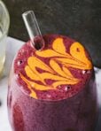A close-up image of the blueberry lemon pie smoothie, with a drizzle of almond butter on top of it