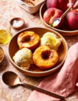 A bowl filled with the single serving olive oil baked peach and two scoops of vanilla ice cream