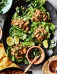 A plate of the peanut chicken lettuce wraps, sitting on a countertop with a small bowl of sauce sitting next to them